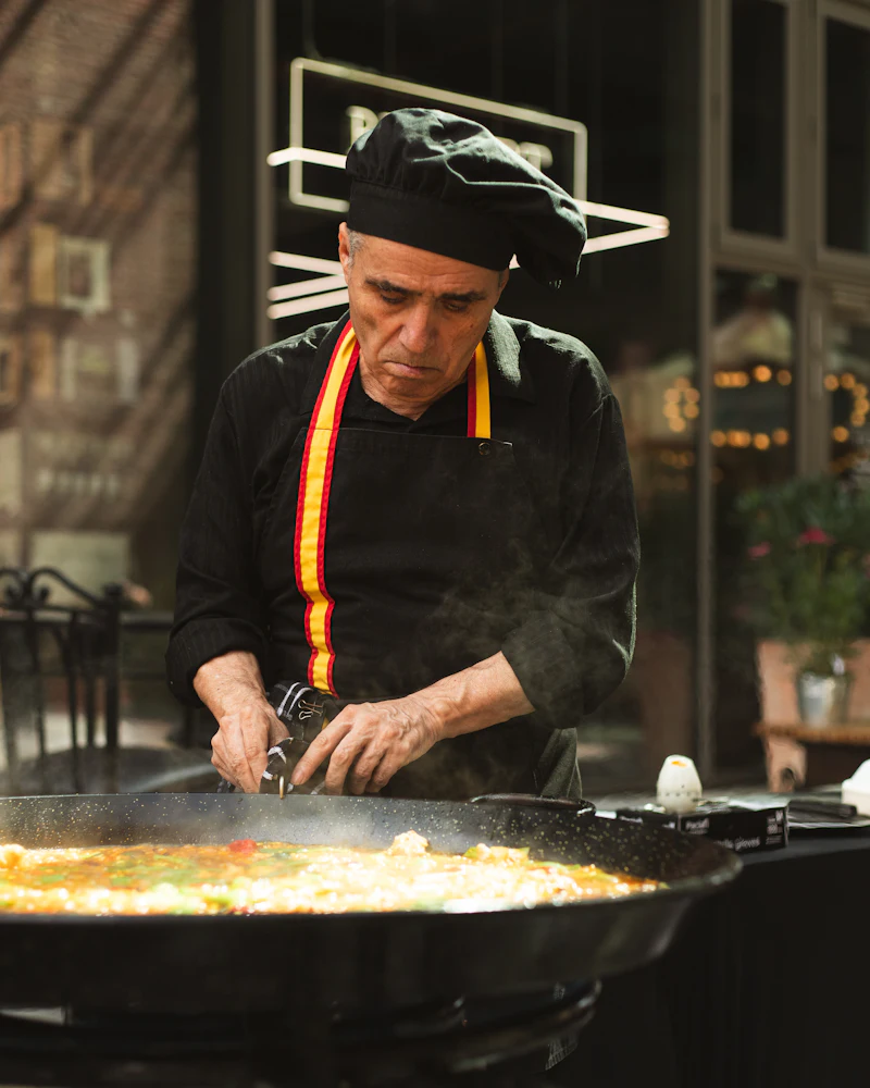 Cocinero removiendo una paellera grande al fuego