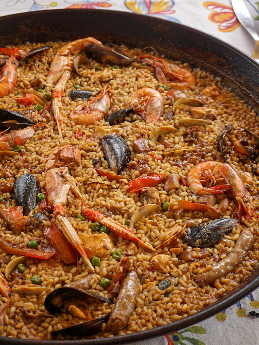 Paella de marisco en la paellera, sobre un mantel de flores